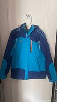 Front view of two-tone blue Camel ski jacket on hanger