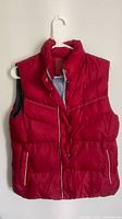 Front view of red puffer vest showing closure, pockets, piping