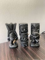 Front view of three black tiki figurines