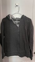 Front view of dark grey zip hoodie on hanger