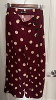Front view of burgundy polka dot wide-leg pants showing button detail