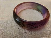 Top view of purple-green peacock motif bangle