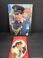 Front cover of larger "Prince Charles" book and front of red "HRH Prince Charles" book