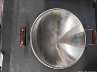 Top view of stainless steel wok showing interior and wooden handles