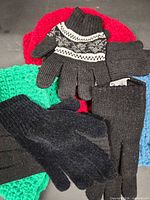 Assorted black knit gloves over red, green and blue knit hats