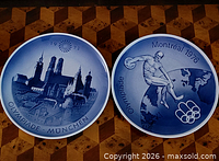 Both Royal Copenhagen Olympic plates side by side on wood surface