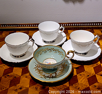 All four Aynsley teacups and saucers displayed on table