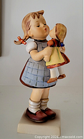 Front view of Goebel Hummel figurine girl holding doll on square base