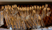Individually wrapped gold flatware laid out showing quantity and types