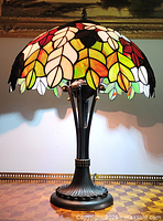 Front view of stained glass table lamp lit, showing shade pattern and base
