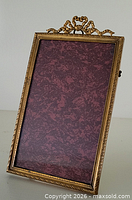 Front view of brass photo frame showing ribbon crest and beaded edge