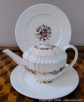 Teapot in front of one plate showing overall design and size relationship