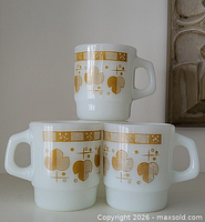 Three white milk glass mugs stacked showing floral meadow pattern