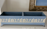 Full view of blue metal planter box with two compartments and white relief figures