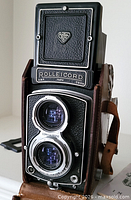 Front view of Rolleicord III camera in leather case, showing twin lenses and nameplate