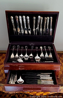 Full view of open storage chest showing two tiers of flatware