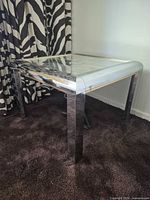 Full view of chrome glass side table on carpet