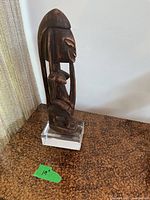 Full view of carved wooden figurine on acrylic base