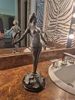 Full view of metal female nude sculpture on bathroom counter