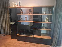 Front view of entire black high-gloss/light wood wall unit with TV placed in front