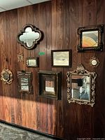 Group of framed mirrors of various shapes mounted on wood paneling