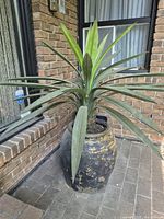 Full view of artificial plant in planter placed on brick floor