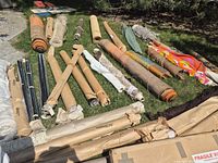 Wide view of numerous fabric, rug and wallpaper rolls laid on grass
