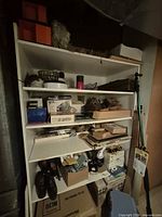 overall shelving with assorted items including shoes, electronics, tripod, boxes