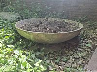 Side view of wide shallow fiberglass/resin planter resting on ground