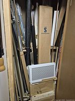 Tall closet showing numerous metal rods, tracks, Simmons box and vent cover