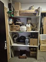 Overall shelving unit with assorted items across three shelves and floor