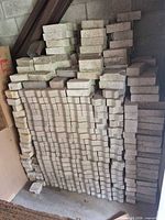 Full stack of pavers against wall showing quantity and mixed colors