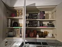 Overall cabinet view showing assorted bowls, glasses, boxed items and accessories