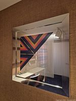 Oblique view of entire mirror showing silver frame and geometric artwork