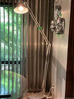 Full view of lamp extended beside wall and table