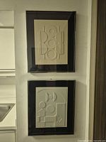 Both framed embossed artworks hanging one above the other