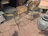 Both round glass side tables showing glass tops and brass bases