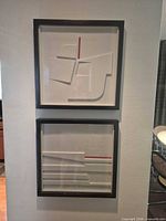 Both framed artworks hung vertically on wall