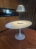 Full view of oval marble dining table with tulip base under pendant light