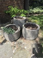 three cylindrical exposed aggregate concrete planters on stone patio