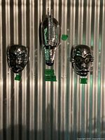 Front view of three chrome wall masks on corrugated backdrop