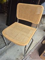 Front view of one chair showing cane seat, back and chrome frame