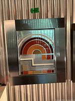 Front view of framed mirrored artwork showing geometric design and metal frame