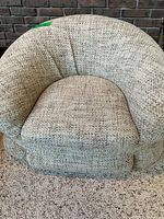 front view of beige bouclé tub armchair showing seat, arms, and fabric texture
