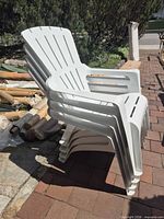 stack of four white plastic patio chairs side view