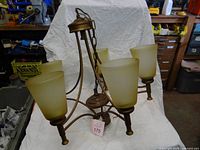 Full view of five-light brown metal chandelier with amber glass shades
