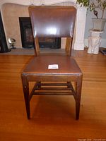 Front view of brown faux leather armless chair with wood frame