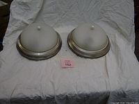 Pair of brushed nickel ceiling lights resting dome-up on fabric backdrop