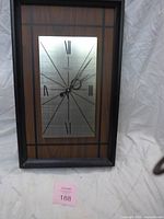 Front view showing wood-grain panel, silver dial, Roman numerals, black frame
