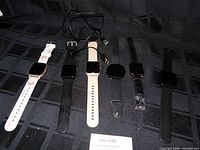 All six smartwatches and charging cable on dark surface